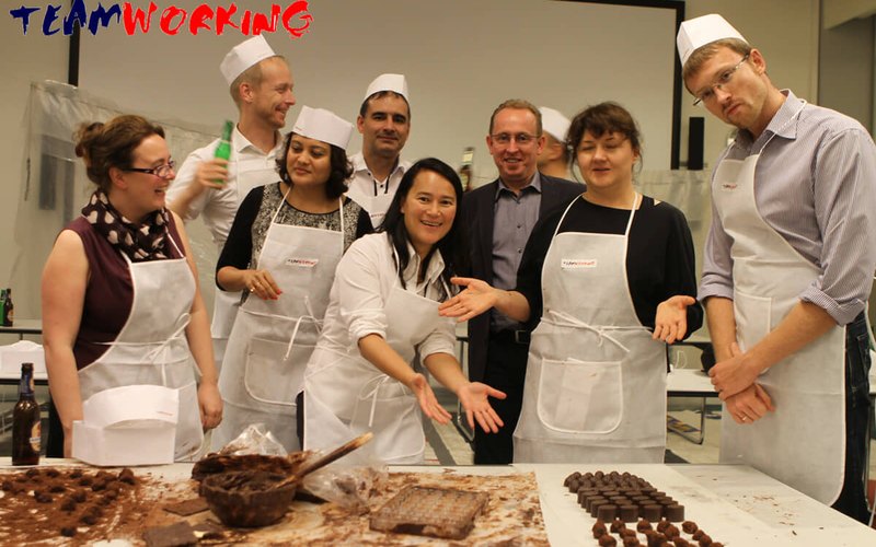 A team in chef whites around a table of chocolates they have just made