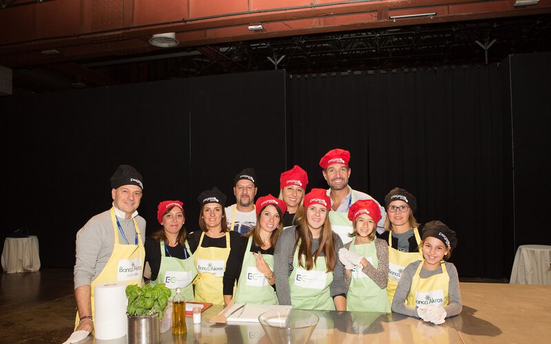 A team in aprons cooking a full dinner menu with a chef