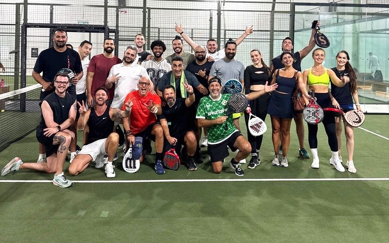 Participants posing with their padel rackets on an indoor court