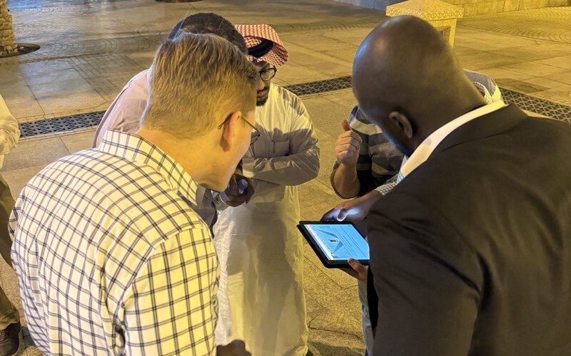 A team gathered around the tablet reading the next clue during an urban game
