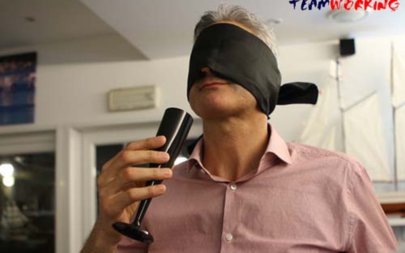 A blindfolded participant nosing the wine during a blind tasting