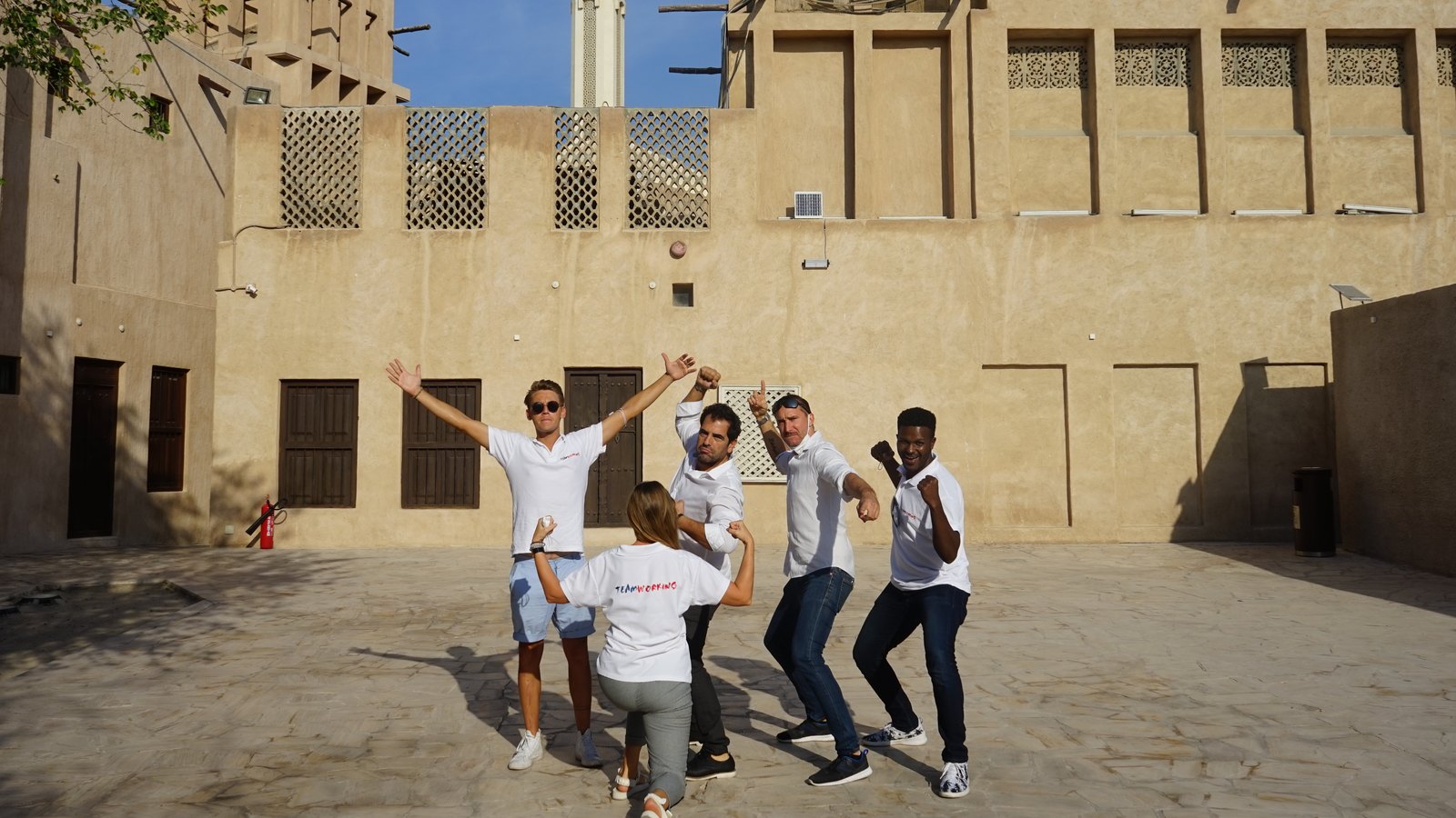 A team striking a pose in a courtyard of the old quarter, wind towers and a minaret behind