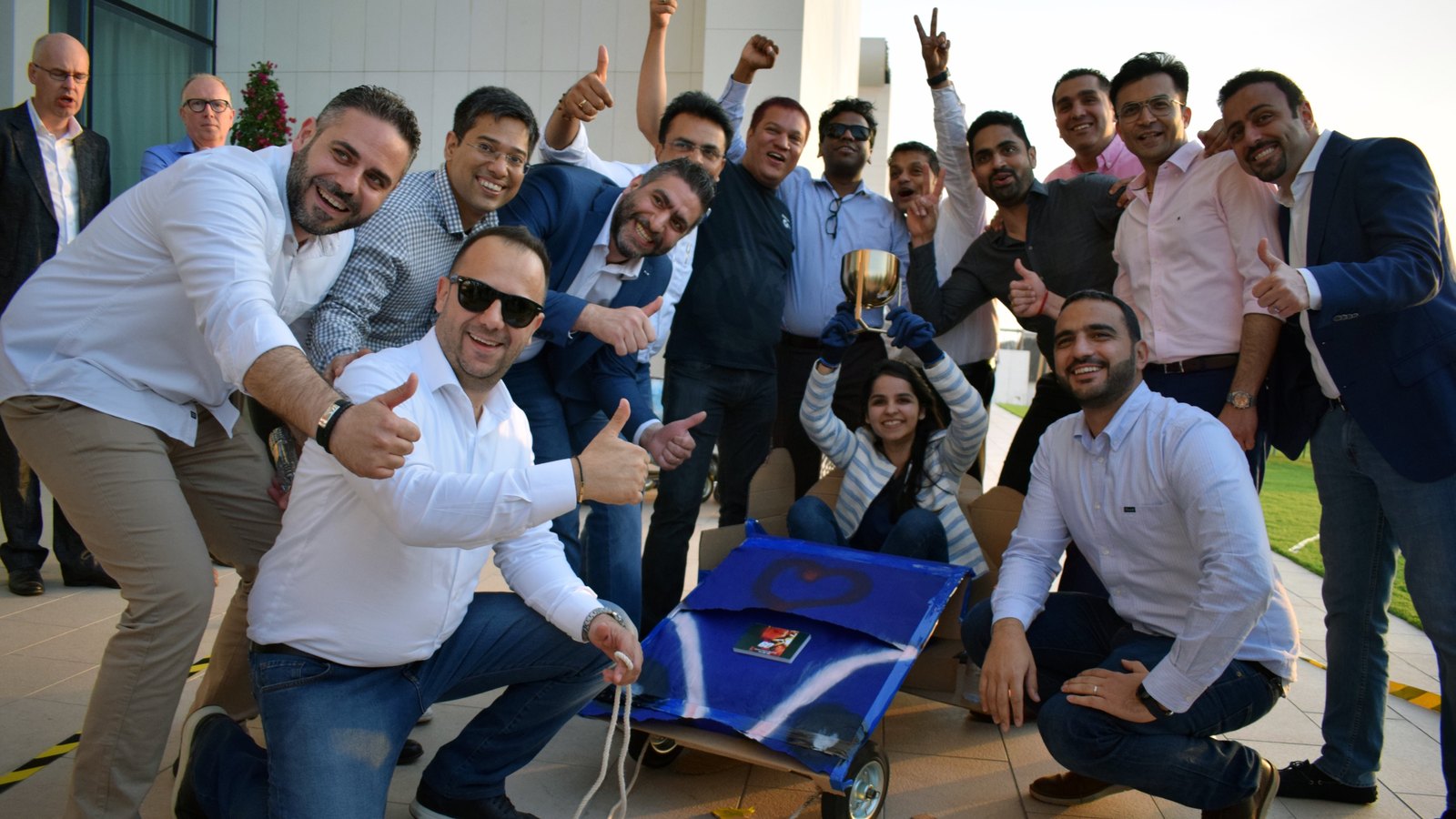A team celebrating around their cardboard cart with one of them holding up the trophy
